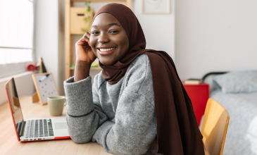 Young lady smiles while sitting at desk on her computer